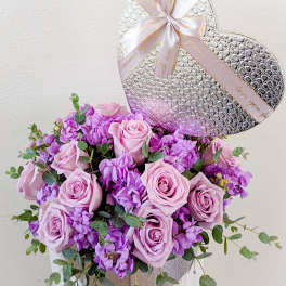 Pink roses and purple flowers in a silver heart-shaped box with a ribbon