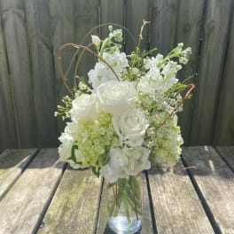 White roses and hydrangeas arranged in a clear glass vase