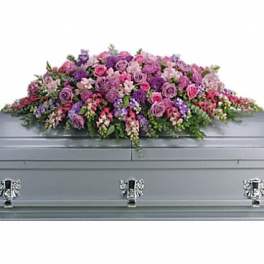 Pink and purple floral casket spray on a gray casket