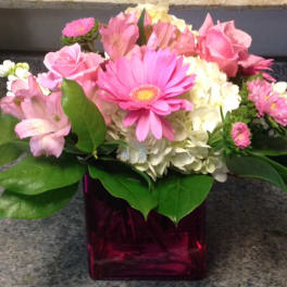 Pink and white mixed flowers arranged in a square glass vase