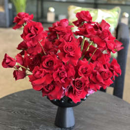 Red roses arranged in a black pedestal vase