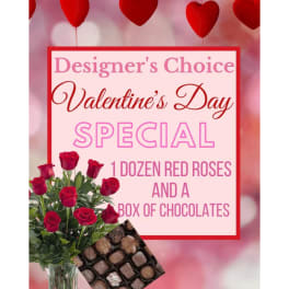 Red roses in a glass vase beside a box of chocolates and a Valentine’s Day sign.