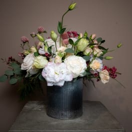 Mixed bouquet of white and blush flowers in a dark metal vase