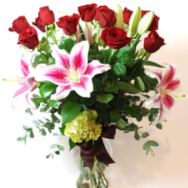 Bouquet of red roses and pink lilies in a clear glass vase