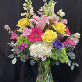 Mixed bouquet of roses, lilies, and gerbera daisies in a glass vase