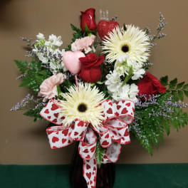 Heart-themed bouquet with red roses, white daisies, and a heart ribbon in a vase
