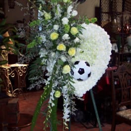 Standing floral tribute with white blooms and a soccer ball centerpiece