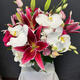 Bouquet of pink and white lilies and orchids in a glass vase