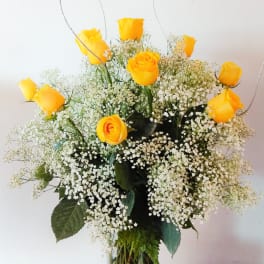 Yellow roses in a clear glass vase with white baby's breath