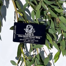 Black Glen Head Flower Shop card resting on long green branches against a white background