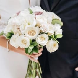 White rose bouquet with pale pink accents and greenery