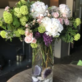 Mixed bouquet of white and pink flowers in a tall glass vase