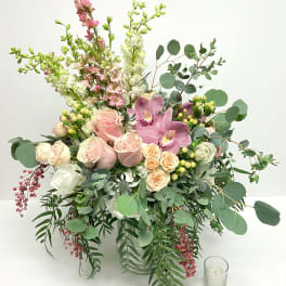 Large pastel bouquet in a clear glass vase with pink roses and orchids