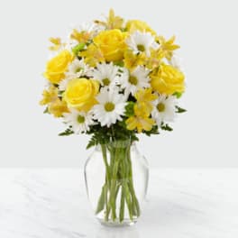 Yellow roses and white daisies in a clear glass vase