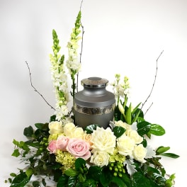 Floral urn arrangement with roses and white blooms around a gray memorial urn