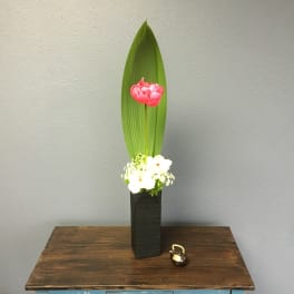 Tall floral arrangement with a pink bloom and white flowers in a black vase