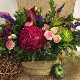 Mixed floral arrangement with pink roses, magenta hydrangea, and purple spikes in a low container