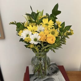 Yellow and white flowers arranged in a clear glass vase