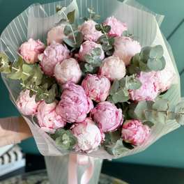 Bouquet of pink peonies with eucalyptus in striped wrapping