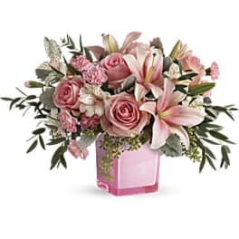 Pink roses and lilies arranged in a pink glass vase