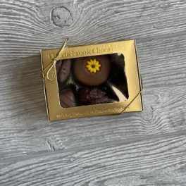 Gold box of chocolates with a small flower decoration on top