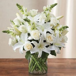 White lilies and roses arranged in a clear glass vase