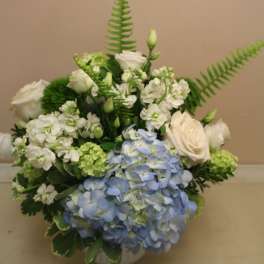 Blue hydrangeas and white roses arranged in a low vase