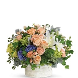 Peach roses and white lilies in a white round container