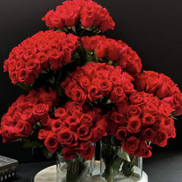 Clusters of red roses arranged in clear glass vases on a round base