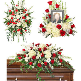 Funeral floral tributes with red and white flowers around a casket and framed photo