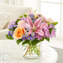 Pink lily and mixed flower bouquet in a clear glass vase
