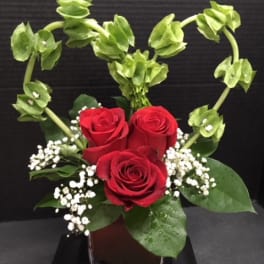 Red roses with baby's breath and green bells of Ireland in a vase