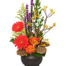 Bright mixed floral arrangement in a dark round vase