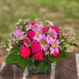 Pink roses and daisies arranged in a glass vase