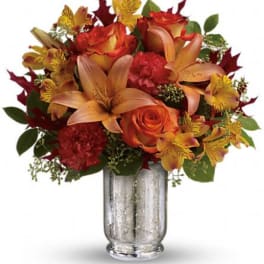 Orange and red floral arrangement in a silver vase