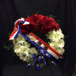 Red roses and white daisies arranged as a wreath with ribbon and medals