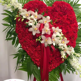 Heart-shaped red floral standing spray with white orchids and ribbon