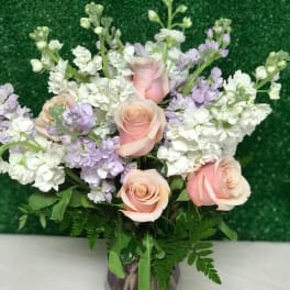 Pink roses and white-lavender flowers in a glass vase