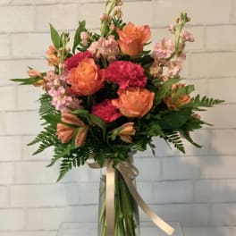 Bouquet of orange roses and pink carnations in a glass vase