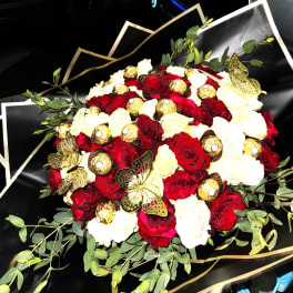 Round bouquet of red and white roses with gold-wrapped chocolates and gold butterflies in black wrapping