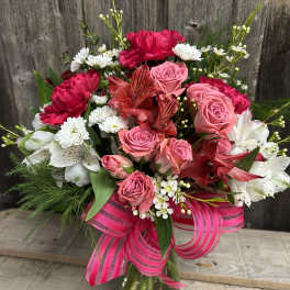 Pink roses and red carnations in a glass vase with a striped ribbon