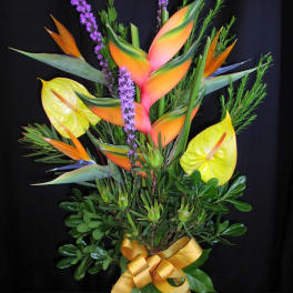 Tropical bouquet with bird of paradise and purple spikes in a glass vase