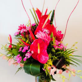 Bright tropical bouquet with red anthuriums in a glass vase