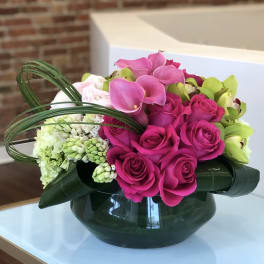 Pink roses and calla lilies arranged in a glass bowl vase