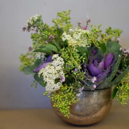 Purple and white floral arrangement in a metallic bowl vase