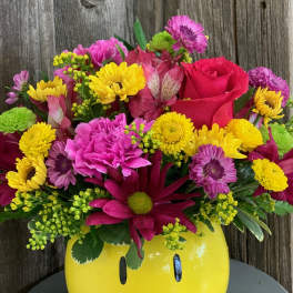 Bright mixed bouquet in a yellow smiley-face vase