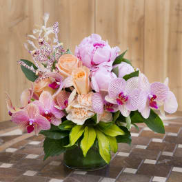 Pink and peach flowers arranged in a glass vase