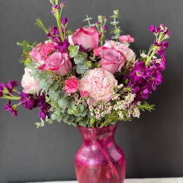 Pink and purple bouquet in a magenta glass vase