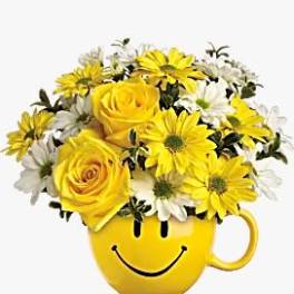 Yellow and white flowers arranged in a smiley-face mug