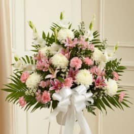 Pink and white floral standing spray with a white ribbon